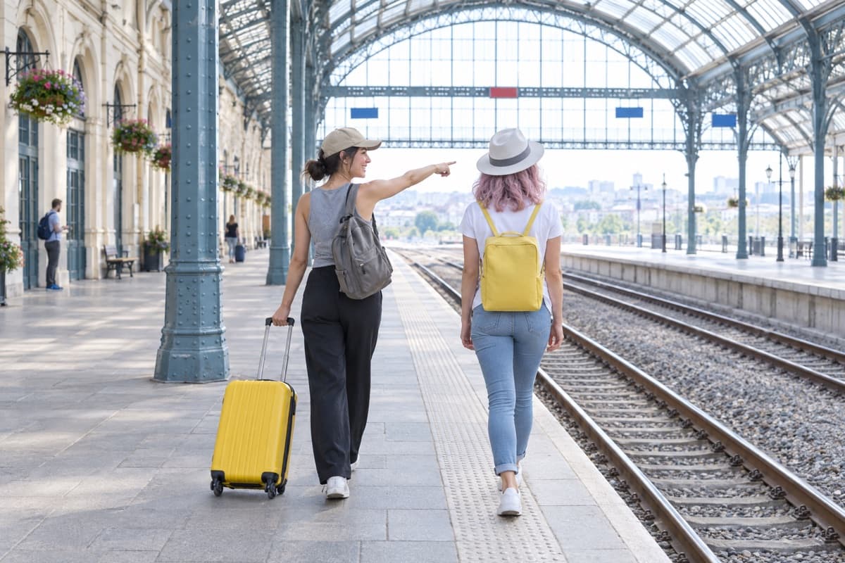 Viajeras con maletas caminando por el andén de una estación de tren