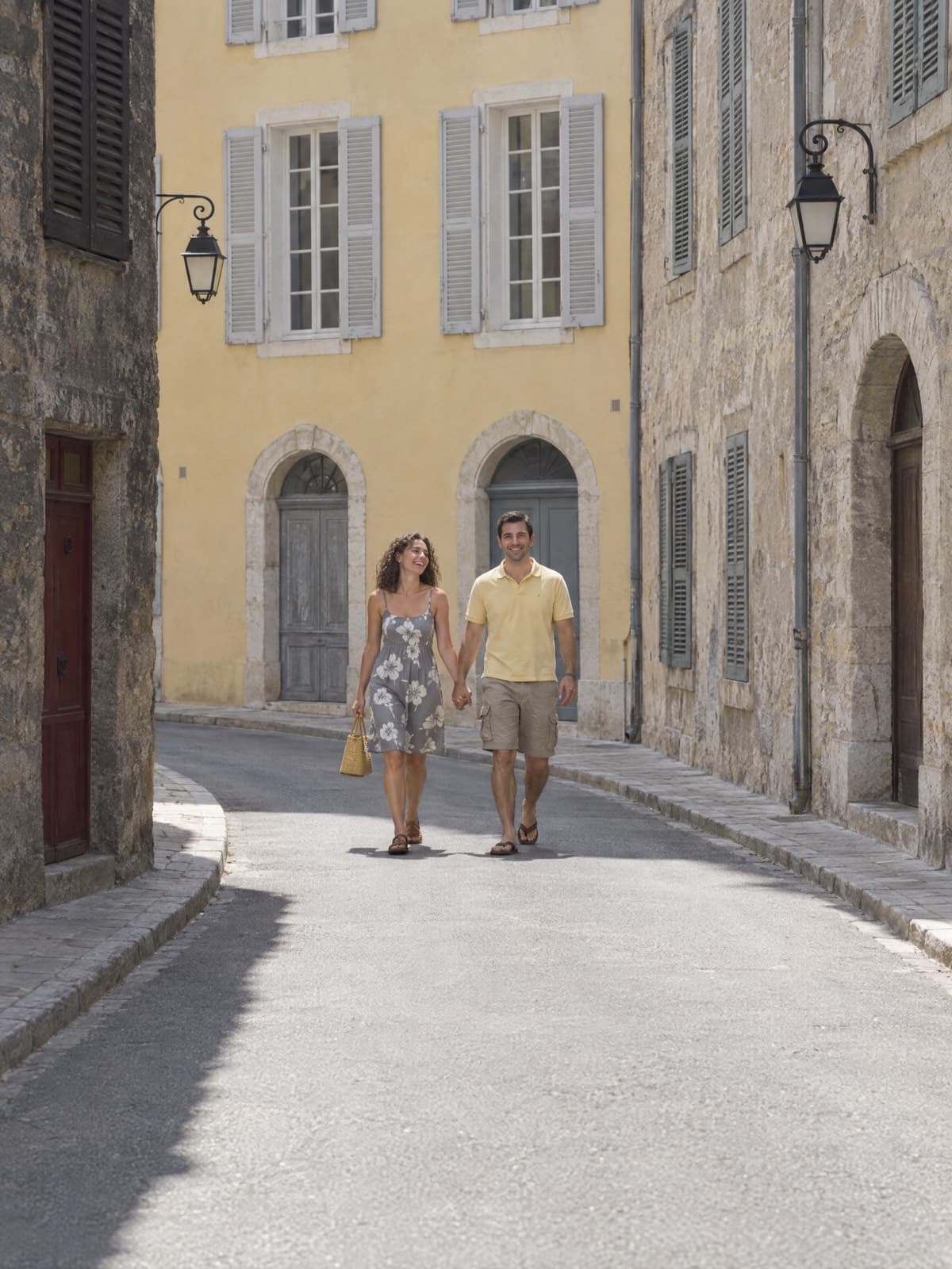 Pareja caminando por una calle soleada de un pueblo europeo